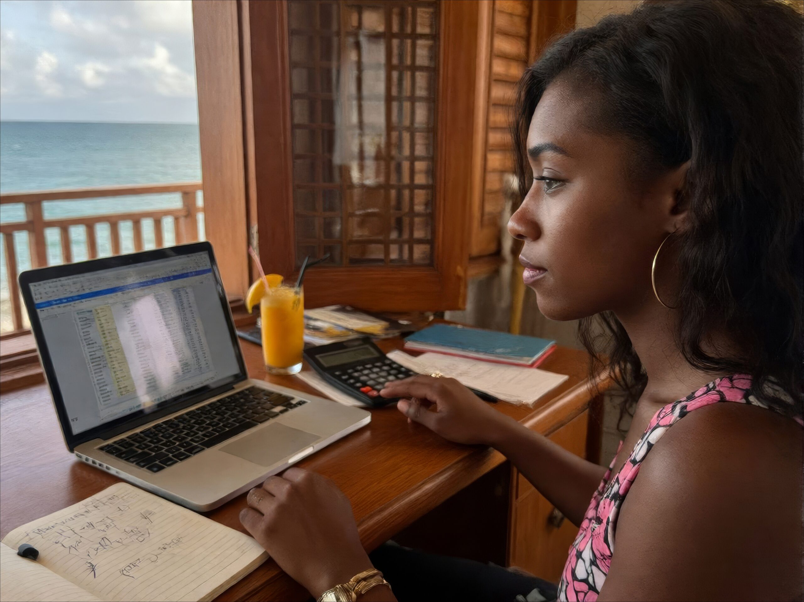 Wooden desk in Zanzibar villa office with laptop showing rental income spreadsheet, calculator, coffee cup and notebook overlooking ocean through window
